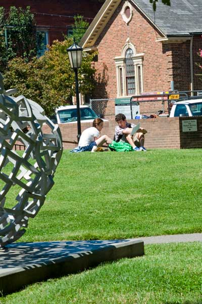 students sitting on the lawn outside harris hall at v.c.u. on a sunny day